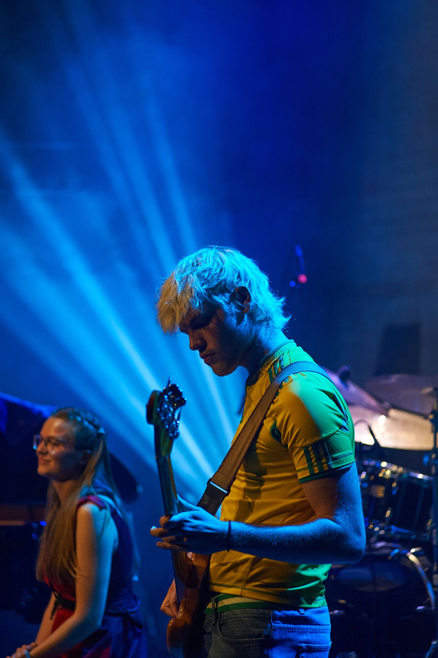 Bassist in gelbem Shirt unter blauen Scheinwerfern